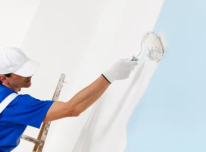 Un peintre professionnel appliquant de la peinture blanche sur un mur bleu avec un rouleau à Argy près de Châteauroux dans l'Indre 36